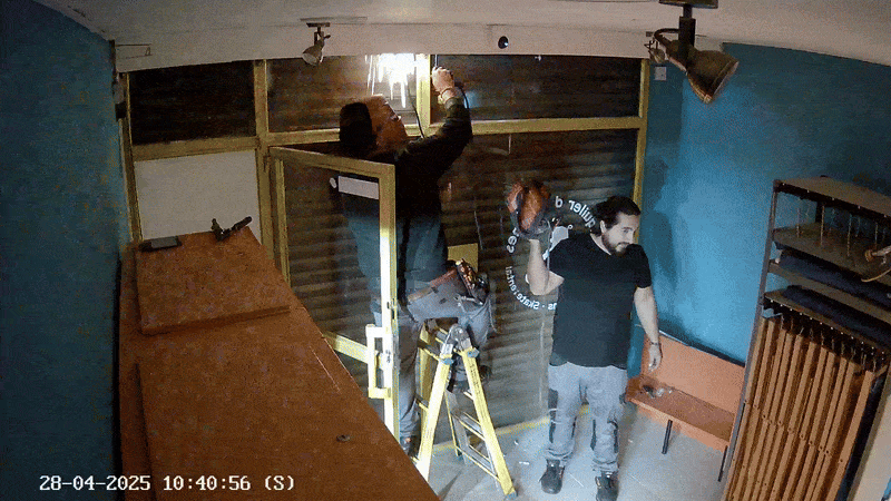 Technicians working on installing automated door blind system to enable hands-free store opening and closing